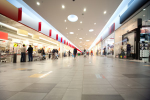 Wide hall and buyers in trading center with shops on both sides